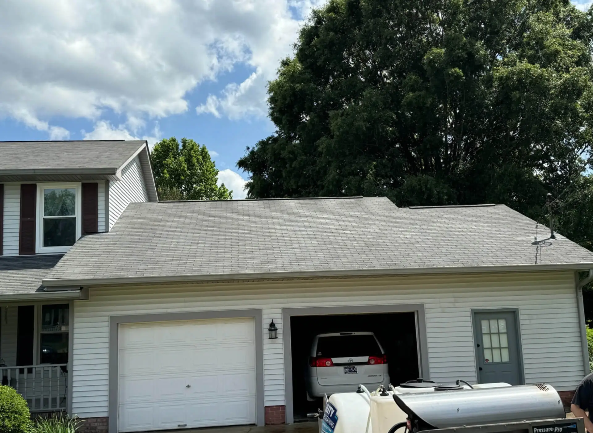 A freshly cleaned residential asphalt shingle roof above a garage after a professional soft washing service.
